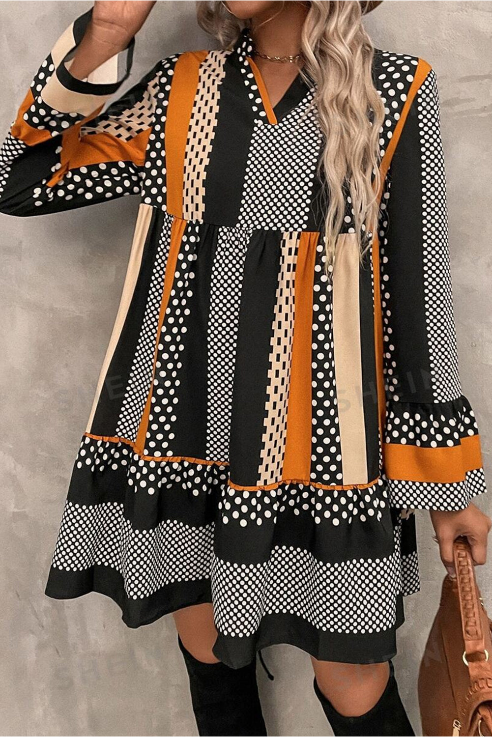 Woman wearing a patterned dress with black, white, and orange colors against a gray background.